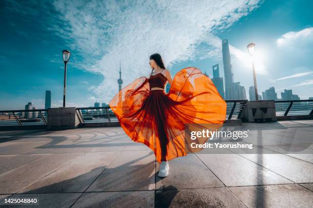 beautiful young woman in red skirt dancing on the shanghai bund in the morning - best female performance stock pictures, royalty-free photos & images