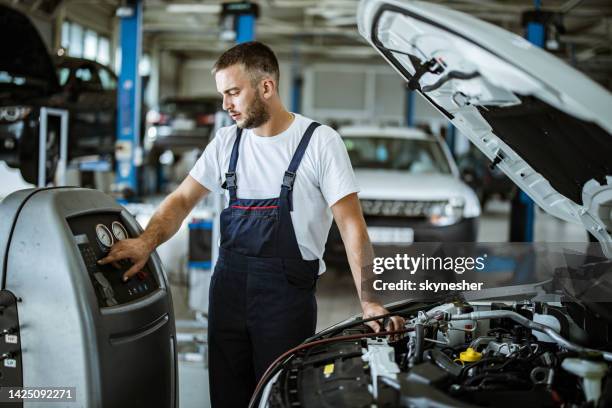 young auto mechanic refueling car ac in a repair shop. - auto mechanic stock pictures, royalty-free photos & images