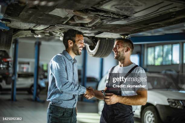 happy customer shaking hands with auto mechanic in a workshop. - undercarriage stock pictures, royalty-free photos & images