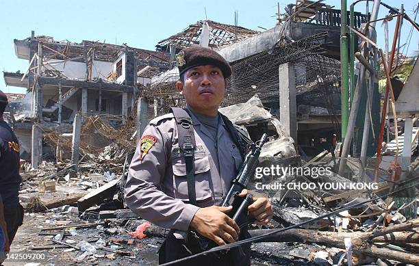 An armed Indonesian policeman guards in front of what remains of the Padi club, in Denpasar, on the Indonesian island of Bali, 13 October 2002,...