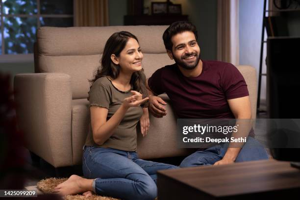 glückliches paar, das das wochenende zusammen verbringt und ein fernsehfoto sieht - indian couple at home stock-fotos und bilder