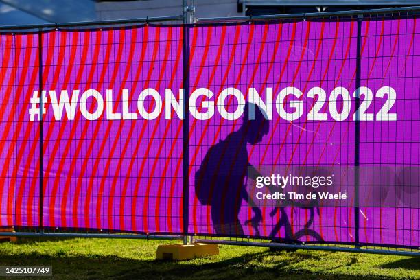 Shadow of an onlooker through a poster on which we read "#Wollongong2022" during the 95th UCI Road World Championships 2022 - Men U23 Individual Time...