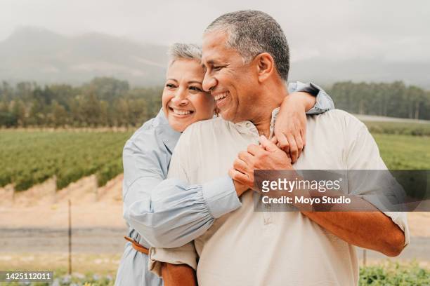 mature couple, hug and bonding on wine farm, nature countryside and agriculture environment for retirement vacation. happy, smile and mexican man and woman in trust, love security and safety embrace - travel real people stockfoto's en -beelden