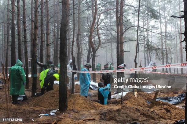 Forensic technicians exhume a grave at the site of a mass graves in a forest during exhumation on September 16, 2022 in Izium, Ukraine. Exhumation of...