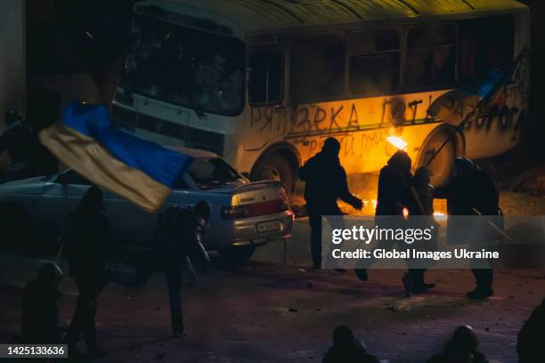Protesters with Ukrainian flags confront with police at barricades from damaged vehicles during anti-government protest in the center of the...