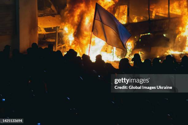 Protesters with Ukrainian flags stand next to barricades from burning vehicles during anti-government protest in the center of the Ukrainian capital...