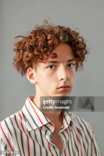 ritratto d'arte in studio ravvicinato di un ragazzo adolescente di 15 anni in una camicia a righe su uno sfondo grigio - tre quarti anteriore foto e immagini stock