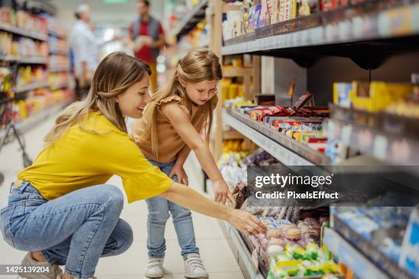 mutter und tochter im supermarkt - süßigkeit stock-fotos und bilder