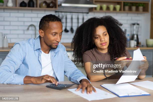 a couple looking unhappy while going through paperwork at home - bank statement stock pictures, royalty-free photos & images