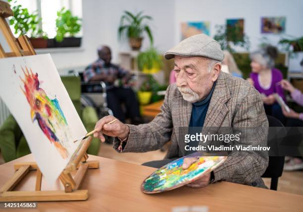 indoor art lesson in retirement care home - elderly cognitive stimulation therapy stockfoto's en -beelden