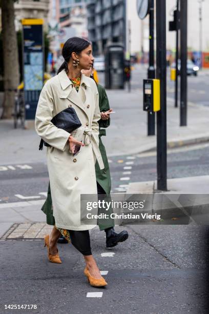 Guest wears black bag, double breasted trench coat outside Simone Rocha during London Fashion Week September 2022 on September 18, 2022 in London,...