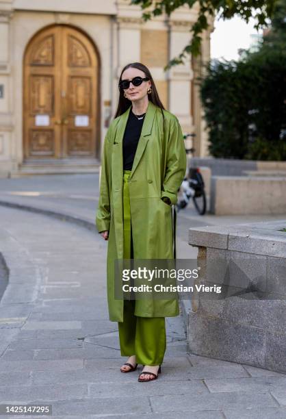 Guest wears green leather coat, pants outside Simone Rocha during London Fashion Week September 2022 on September 18, 2022 in London, England.