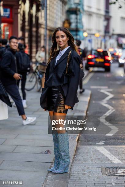 Tamara Kalinic wears glitter boots, black skirt, navy blazer, white button shirt, bag outside Erdem during London Fashion Week September 2022 on...