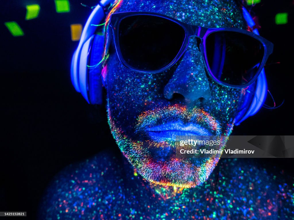 A DJ with headphones under UV lights