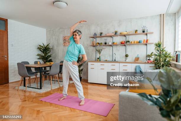 senior woman stretching before a workout at home - bodyweight training stock pictures, royalty-free photos & images