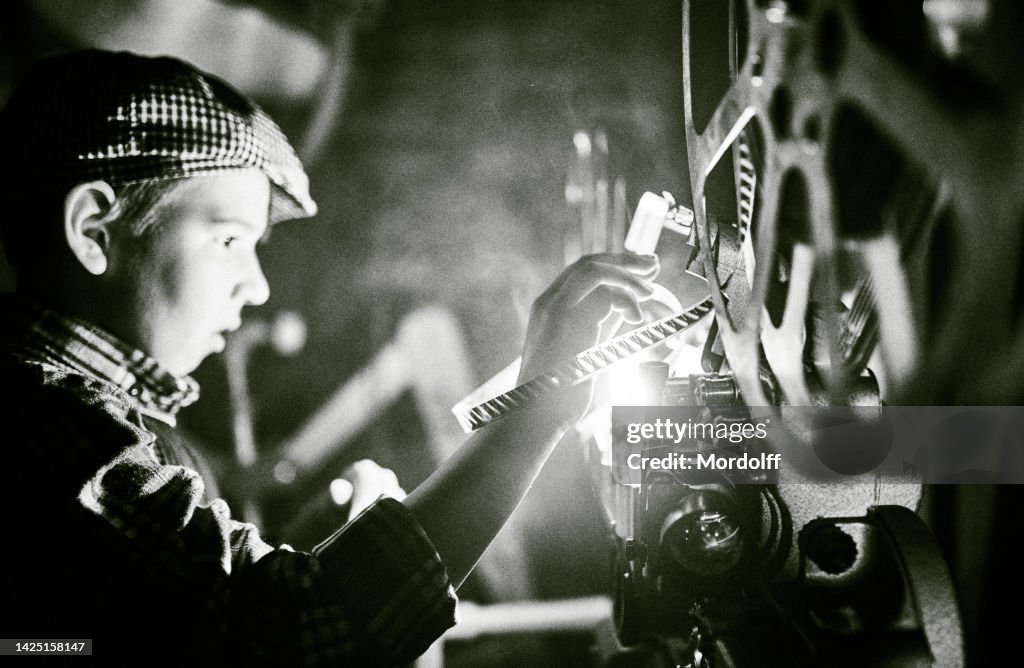 Boy Projectionist Is Loading The Reel Of a Movie into Film Projector