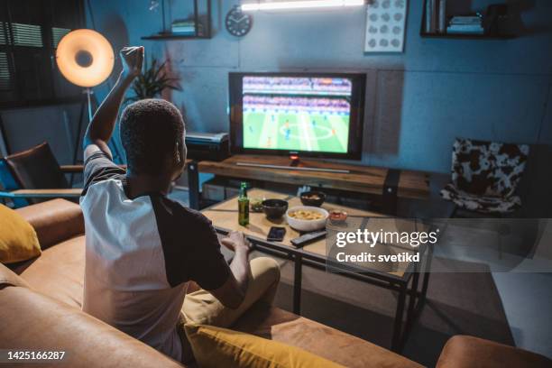 watching soccer game at home - african american watching tv stock pictures, royalty-free photos & images