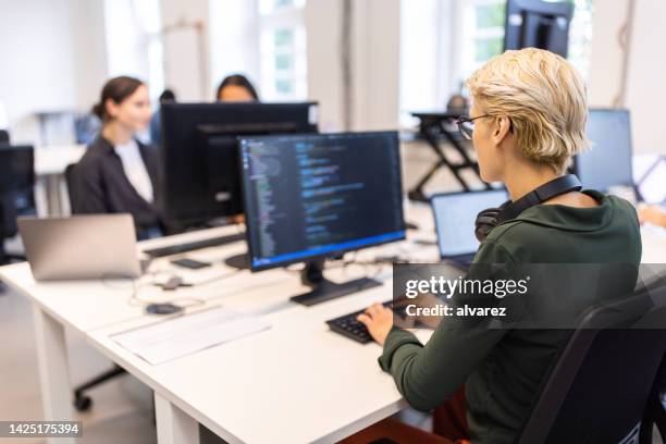 woman software programmer coding on computer at startup - developer stockfoto's en -beelden