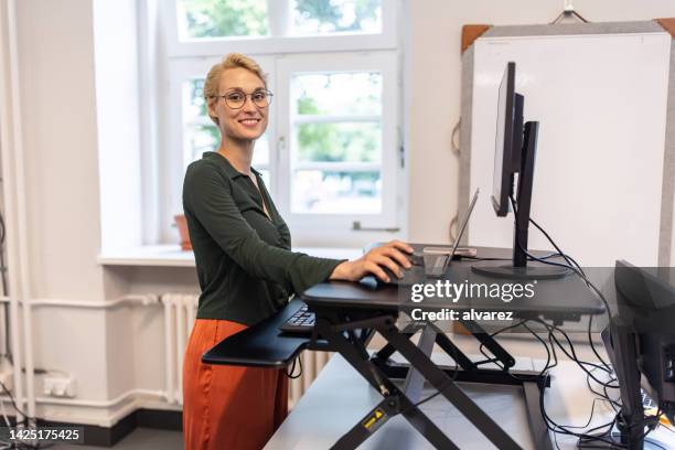 portrait of a businesswoman working at her standing desk at startup office - ergonomie stockfoto's en -beelden