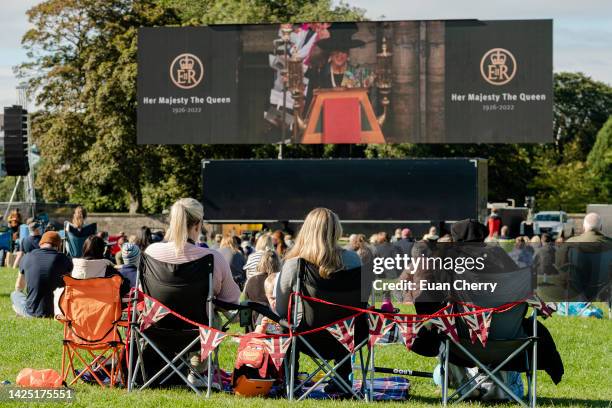 Members of the public watch Queen Elizabeth II's state funeral on a tv screen in Holyrood park on September 19, 2022 in Edinburgh, United Kingdom....