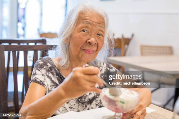 senior filipino woman eating ice cream - filipino stock pictures, royalty-free photos & images