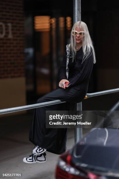 Guest is seen wearing white sunglasses, black long dress, silver necklace, silver leather Balenciaga Cagole bag and white/black sneakers outside COS...