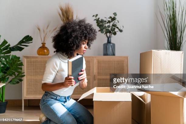 beautiful woman unpacking her favorite books in her new apartment. - arrange stockfoto's en -beelden