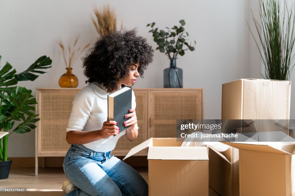 Beautiful woman unpacking her favorite books in her new apartment.