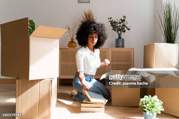 beautiful woman unpacking her favorite books in her new apartment. - new house imagens e fotografias de stock