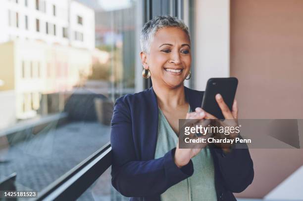 senior, phone and happy woman from india with mobile looking at web content with a smile. happy elderly indian female using technology to scroll internet and social media app or to start a video call - penn commercial business stock pictures, royalty-free photos & images