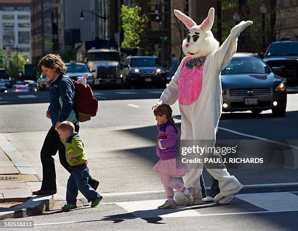 Person in a "Easter Bunny" suit is helped across I Street April 6 in Washington, DC. The anti-poverty advocates had been attending a protest in...