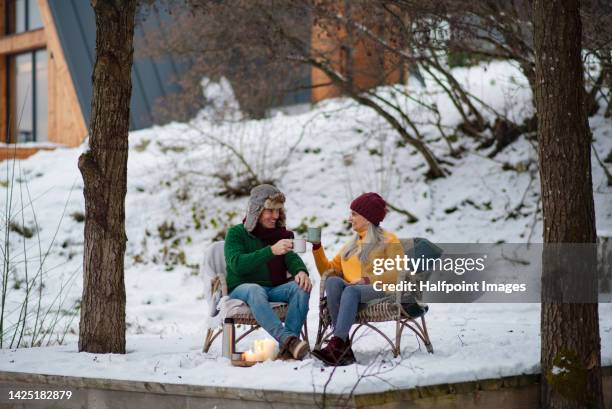 happy seniors drinking tea, smiling, talking having nice time together in winter, outdoor scene with snow. - hygge stockfoto's en -beelden