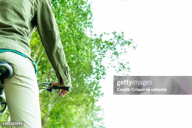 rear view of woman riding a bicycle, rural scene - fahrradsattel stock-fotos und bilder