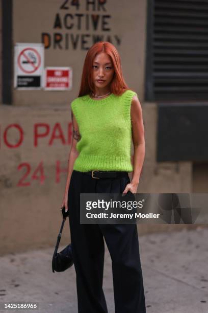 Guest is seen wearing light green sleeveless wool knit sweater, black leather belt, black suit pants and a black leather bag outside COS during New...