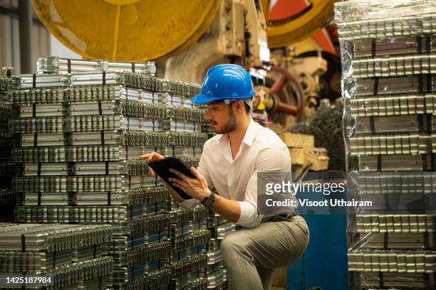 engineer with tablet checking equipment condition against machine environment in factory. - polimero foto e immagini stock