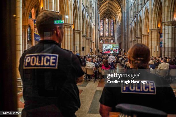 Two police offices watch as members of the public gather to watch large screen live BBC TV coverage of the funeral of Queen Elizabeth II at Truro...