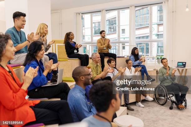 diverse group of entrepreneurs clapping hands during a startup conference - lob hairstyle stock-fotos und bilder