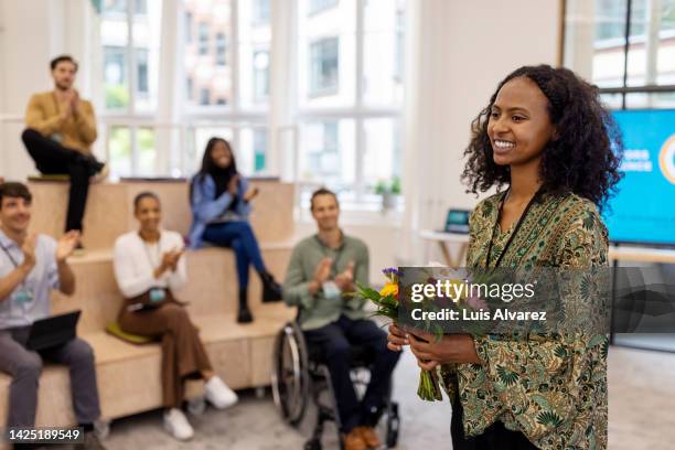 smiling woman entrepreneur with bouquet thanking the audience at startup conference - danke blumen stock-fotos und bilder