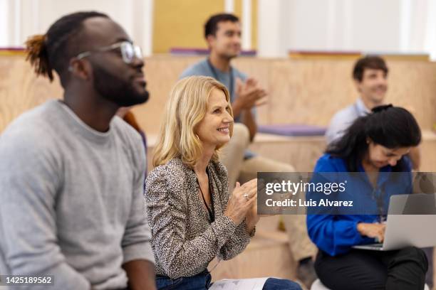 group of multiracial men and women applauding in a seminar - germany womens team presentation stockfoto's en -beelden