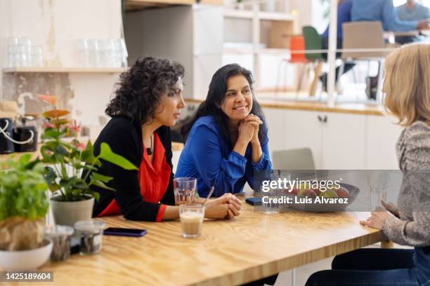 three businesswomen talking during coffee break at office cafeteria - coffee break party photos et images de collection