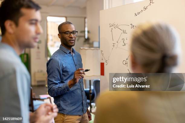 african businessman giving a presentation to colleagues at startup office - unternehmer stock-fotos und bilder