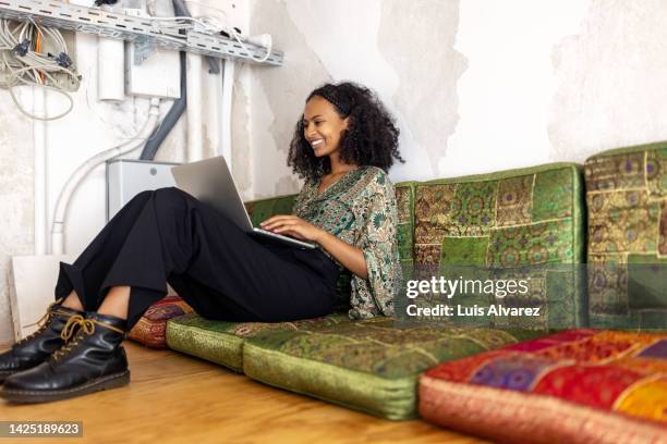 young woman sitting in office lounge working on laptop - business casual dress code stock pictures, royalty-free photos & images