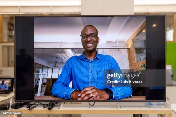 african man seen on television screen during video call meeting - man facing camera stock pictures, royalty-free photos & images