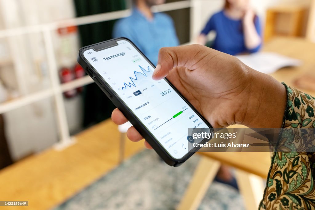 Close-up of woman trading stock online on mobile phone