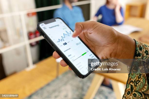 close-up of woman trading stock online on mobile phone - cambio valuta foto e immagini stock