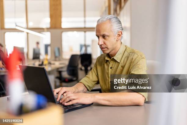 mature man working on laptop in a modern office - khaki - fotografias e filmes do acervo