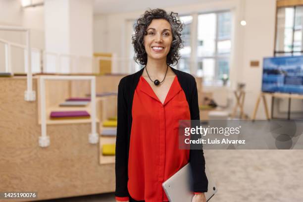 portrait of confident mature businesswoman standing in office seminar hall - red dress shirt stock pictures, royalty-free photos & images