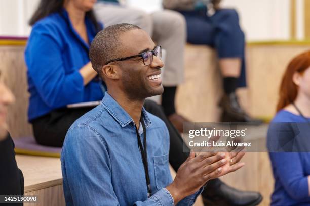 young businessman applauding during seminar at office - african hands clap stock-fotos und bilder