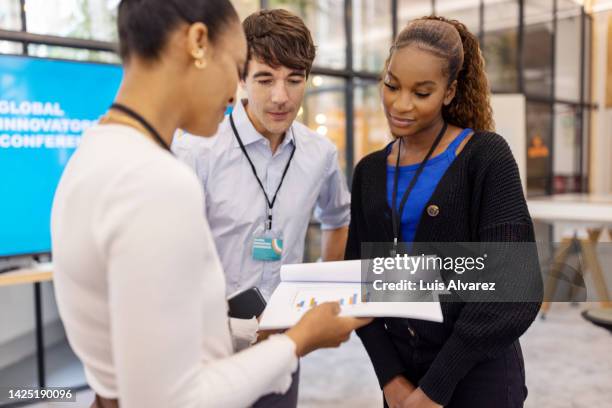 businesswoman showing some reports and discussing with people at conference - look of the day launch party stock pictures, royalty-free photos & images