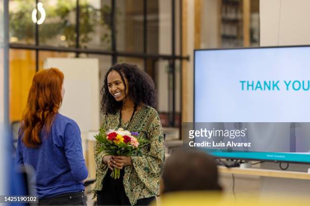 young woman entrepreneur receiving bouquet from a colleague at seminar - receiving flowers stock pictures, royalty-free photos & images